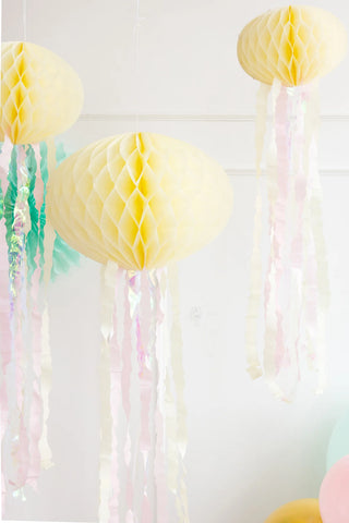 Yellow paper lanterns with pastel-colored streamers and My Mind's Eye Honeycomb Jellyfish Set hanging from the ceiling against a bright, light background.