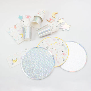 A collection of party supplies for a special occasion, featuring cups, Iridescent Paper Plates, and napkins adorned with stars, moons, and colorful sparkles on a white background from Loop by Frankie.