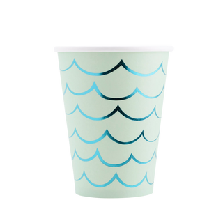 A Mermaid Tail Paper Party Cup from My Mind's Eye with a light blue wave pattern on a striped black and white background, perfect for an under the sea party.