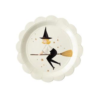 A whimsical illustration of a witch riding a broomstick graces the center of a scalloped-edge Witches Paper Plate Set by My Mind's Eye, surrounded by golden stars on a clean, white background.