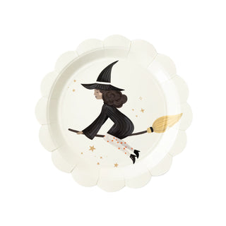 A whimsical Witches Paper Plate Set by My Mind's Eye featuring an illustrated witch in mid-flight on her broomstick, surrounded by a scattering of golden stars against an ivory background, bordered by a ruffled plate edge reminiscent
