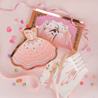 A whimsical party set with a pastel color scheme, featuring illustrated unicorn plates, a pink napkin, and wooden cutlery with pink handles, all sprinkled with colorful confetti on a soft pink surface.