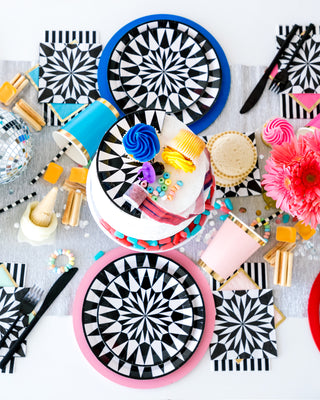 A vibrant and colorful tabletop boasting a playful mix of patterned plates, an assortment of festive decorations, bright flowers, and party favors, all arranged in a lively, celebratory composition.