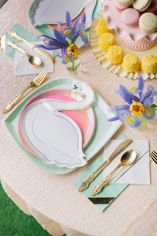 A vibrant table setting featuring whimsical swan plates, gold cutlery, and a harmonious palette of pastels with floral accents, creating an elegant scene for a delightful springtime gathering.