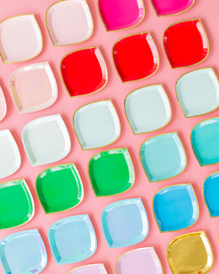 A colorful array of square and round plates with various pastel and bright hues neatly arranged in a pattern on a pink background, evoking a cheerful and festive mood.