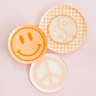 Three decorative plates with peaceful and happy motifs, including a smiley face, a yin-yang symbol, and a peace sign, against a soft pink background, conveying a vibe of harmony and joy.