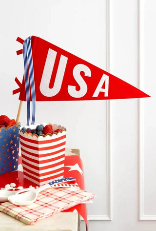 Red pennant with "USA" text next to striped containers with berries and a star-patterned cover on a table.