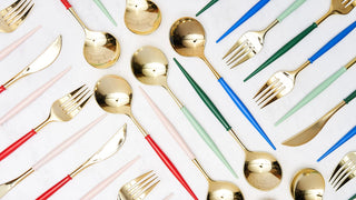 An array of pastel-handled cutlery with golden heads, including forks, knives, and spoons, is neatly arranged diagonally on a white background, showcasing a modern and elegant dining set design.
