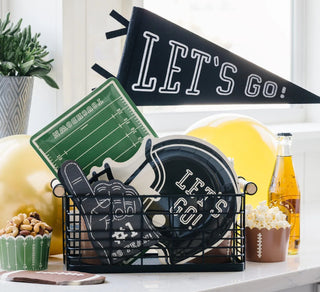 A festive game day setup with snacks, featuring a "let's go!" pennant, a themed bottle, a football playbook napkin, and decorative items showcasing team spirit.