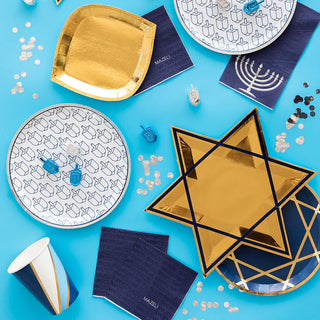 A festive hanukkah-themed tabletop featuring star-shaped plates, dreidel decorations, and elegant blue and gold tableware, celebrating the jewish holiday with a modern twist.