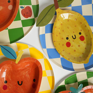 Colorful plates with cartoon faces featuring images of an apple and a lemon on a checkered background.