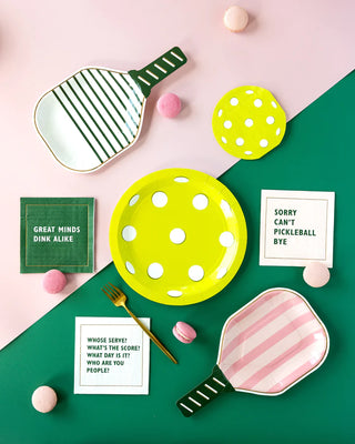 An artistic flat lay of ping-pong paddles and plates styled to mimic the equipment, accompanied by playful phrases related to the sport, on a dual-tone background.