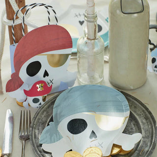 A pirate-themed table setting featuring skull and eyepatch designs on plates and napkins, with gold coin accents and a message-in-a-bottle centerpiece, perfect for a swashbuckling celebration.