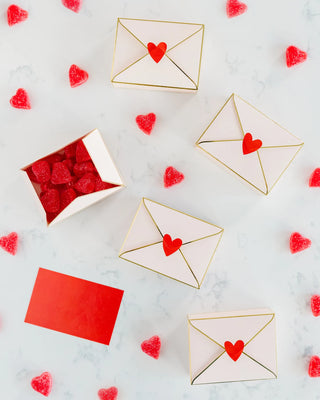 Envelopes adorned with heart seals and a scatter of candied hearts create a sweet valentine's day-themed composition against a marble backdrop.