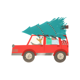 A red car is carrying a large Christmas tree on its roof, with presents visible inside. There is a reindeer in the driver's seat, and Meri Meri's Driving Reindeer Napkins are scattered around for added festive cheer.