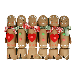 Six cheerful gingerbread people crackers from Meri Meri, each featuring smiling faces, red hearts, and vibrant buttons alongside plaid bow ties. These Gingerbread Crackers are perfect for adding charm as a festive table decoration in any setting.