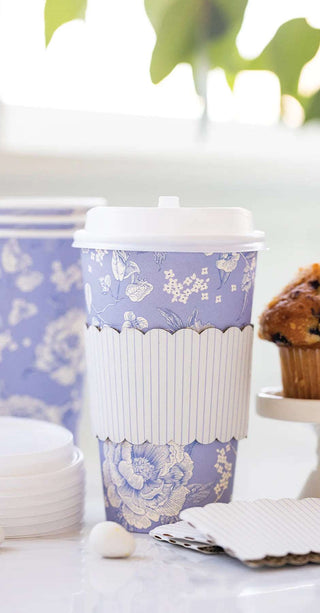 Decorative disposable Blue Pinstripe Floral To-Go Cup by My Mind's Eye on a table with a muffin and plates in the background.