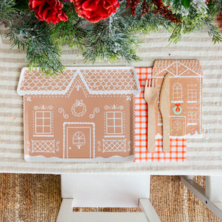 Create a festive holiday table setting with Daydream Society's Baking Spirits Bright collection, featuring gingerbread house-themed plates and their tall guest napkins, complemented by wooden cutlery and a red checkered placemat. Top it all off with festive greenery to add that perfect touch of holiday cheer.