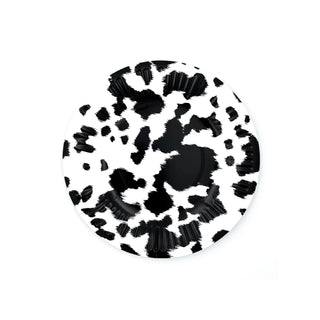A black and white abstract patterned Party West Black Cowhide disposable dessert plate with a centralized dark spot and splattered, ink-like designs sprawling outwards, isolated on a white background.