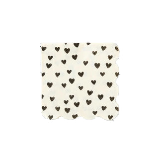 A square fabric swatch with scalloped edges, featuring a polka dot-like pattern of small black hearts against a cream background, is showcased against a solid black backdrop. This piece serves as an Black Hearts Cocktail Napkin by My Mind's Eye.