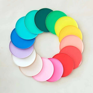 A Blush Plates - 9 inch color wheel designed in San Francisco by Oh Happy Day, composed of variously shaded paper plates arranged in a circular gradient, transitioning from cool to warm hues, creating a harmonious spectrum.