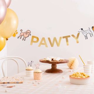 A table is set for a party with cupcakes, popcorn, and iced cookies. Gold balloons and the Bow Wow Banner from Daydream Society, adorned with die-cut puppy dog decorations, are displayed in the background.