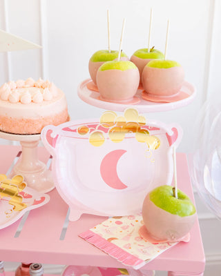 Pink-themed dessert table featuring a cake, caramel-dipped apples presented on My Mind's Eye Cauldron Shaped Plates, and pink napkins adorned with gold decorations set on a pink tray. Perfect for adding a touch of whimsy to any Halloween party!