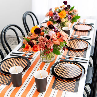 A black and orange Halloween table setting with Check It! Halloween Dessert Plates by Jollity & Co and napkins.