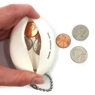 A hand holds a white, shell-shaped rubber coin purse labeled "Three Potato Four" containing coins. More coins are placed on the white surface next to this vintage-inspired Coin Pouch - Thrifting Money.