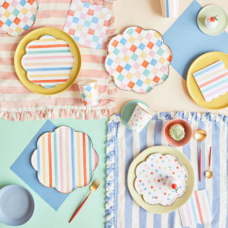 A vibrant table setting featuring pastel checkered, striped, and polka dot plates, along with Meri Meri's Colorful Pattern Cups, decorative napkins, and placemats arranged on a pastel-colored surface. The brushed effect adds a touch of elegance to the overall presentation.