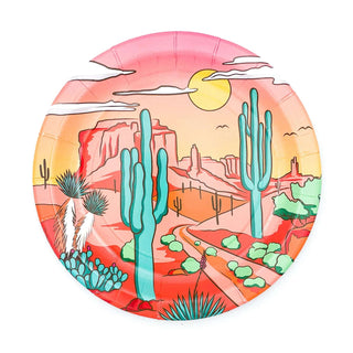 A vibrant, hand-painted ceramic plate featuring a desert scene with saguaro cacti, plateaus, a winding path, and a warm, setting sun casting a peaceful glow over the landscape from Party West's Desert Scene Dinner Plates.