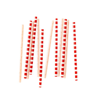 A scattered group of wooden chopsticks and festive Elf Reusable Straws by My Mind’s Eye on a white background.