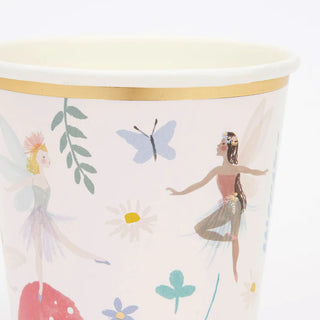 The Fairy Cups by Meri Meri are charming paper cups adorned with illustrations of two fairies, flowers, leaves, and a butterfly on a light background. They feature golden foil stars and a gold rim near the top, making them perfect for fairy party cups.