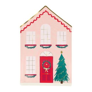 The Festive House Plates by Meri Meri feature a charming illustration of a pink house with a red door, adorned with Christmas wreaths on the windows. A beautifully decorated tree stands beside the door, perfectly capturing the charm of wintry houses.