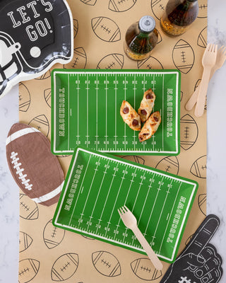 The Football Kraft Table Runner by My Mind's Eye transforms any tailgating gathering with football field plates, mini footballs, snacks, drinks, wooden cutlery, and playful paper decorations for a vibrant football-themed setup.