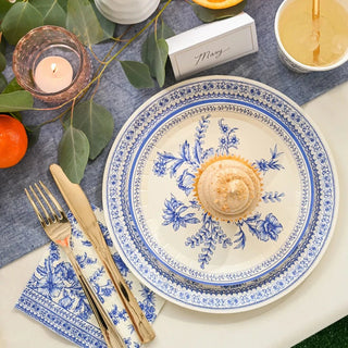 A blue and white table setting with French Toile Cocktail Napkins, a cupcake, and oranges, inspired by Provençal style from Coterie Party Supplies.