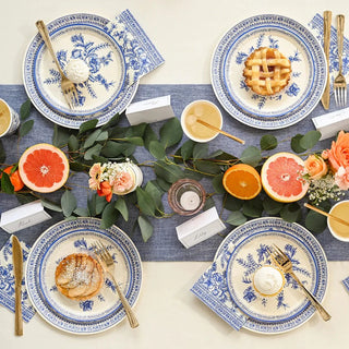 A Coterie Party Supplies French Toile Large Plates table setting with oranges and grapes, featuring a blue and white color scheme.
