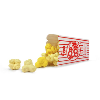 A box of Fresh Popcorn Erasers by Fred and Friends lies on its side, with several pieces of perfectly detailed yellow and white popcorn-shaped erasers spilling out.