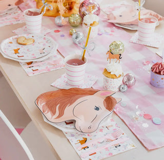 A table setup decorated for a children's pony party features horse-themed plates and Pony Tales Large Napkins from Daydream Society, striped cups with straws, cupcakes with unicorn toppers, and festive ornaments and confetti.