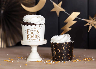 Two Gold Foil Hocus Pocus Food Cups cupcakes on a stand with golden decorations by My Mind's Eye.
