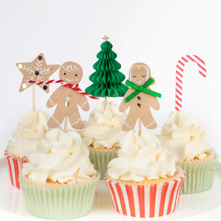 Frosted cupcakes with white icing, featuring festive toppers such as stars, gingerbread figures, trees, and candy canes. Ideal as a creative gift or to enhance your holiday treats alongside the Meri Meri Gingerbread Cupcake Kit.