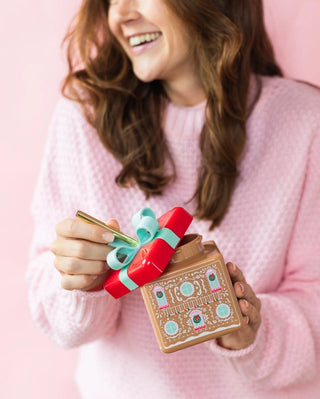 A woman holding a Packed Party Gingerbread House Novelty Sipper embodies the Christmas spirit.