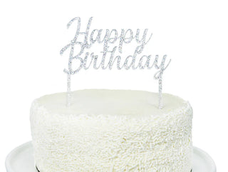 A white frosted cake adorned with Merri's Happy Birthday Silver Acrylic Topper.