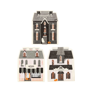 A striking illustration featuring three distinct Halloween-themed houses, each adorned with pumpkins, a bat, and a ghost, and including a "Witches" shop sign. These houses exhibit unique spooky elements and exceptional designs that are ideal for setting the ambiance at your Halloween party. Pair them perfectly with the Haunted House Napkin Set from My Mind’s Eye for an extra eerie touch.