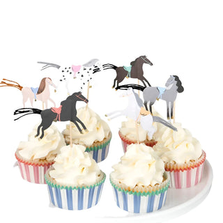 The Meri Meri Horse Cupcake Kit features six cupcakes adorned with charming horse toppers and elegant white frosting, showcasing the artistry of a champion cupcake maker. They are beautifully arranged on a white cake stand.