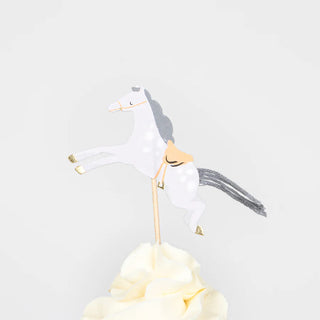 A cream-colored frosting swirl crowned with a paper horse decoration on a stick, created using the Horse Cupcake Kit by Meri Meri.