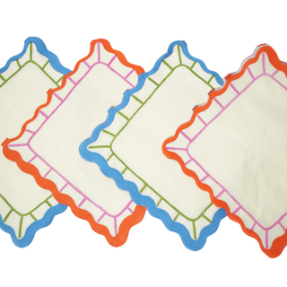 Four cool white Art Party Napkins by Pop! Party Supplies with multicolored scalloped edges in blue, orange, green, and pink are arranged in a diagonal overlapping pattern. Crafted from sustainable FSC paper, these artistic prints add a touch of elegance to any setting.