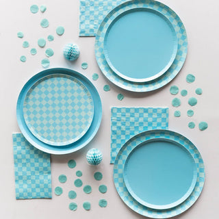 Three Jollity & Co "Check It! Out of the Blue" dessert plates sit on a white surface, surrounded by vibrant blue napkins, confetti, and decorative balls—ideal for completing your party checklist.