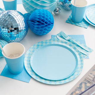 A table set with Jollity & Co's Check It! Out of the Blue Dessert Plates, matching cups, and checkered print napkins. Disco balls and honeycomb decorations add a festive touch.