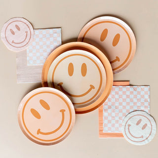 Jollity & Co's Peace & Love Smile Dessert Plates, paired with checkered napkins, adorn the beige surface, radiating a retro-chic vibe.